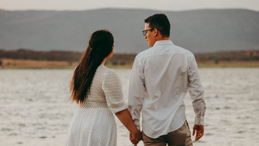 couple holding hands looking towards the mountains
